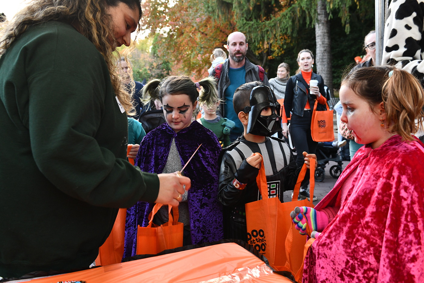 Costumed children receive Halloween treats in their orange tote bags at Boo at the Zoo 