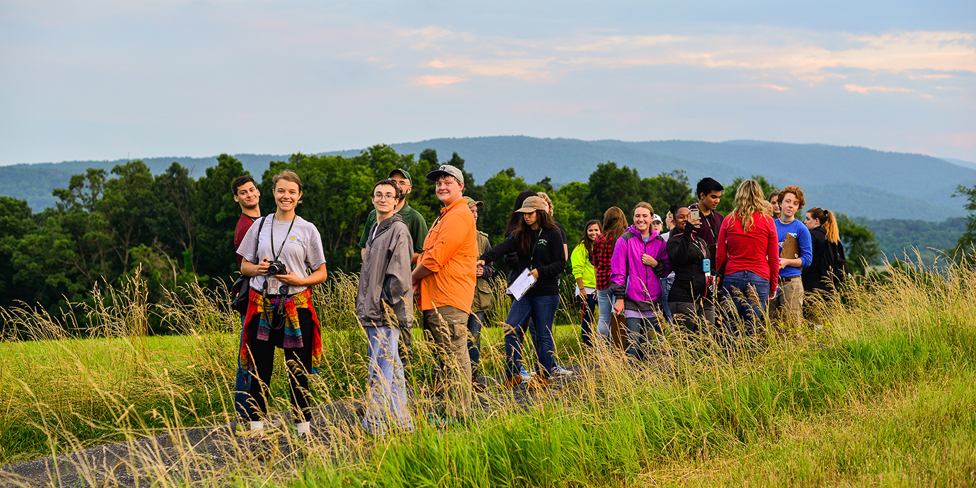 A group of students standing on a grassy mountaintop