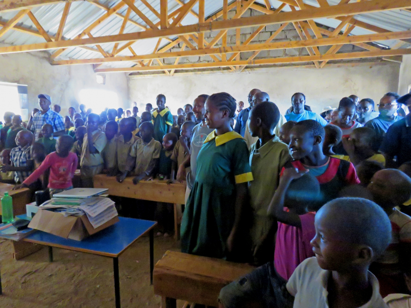 A group of primary school students in a classroom in Laikipia, Kenya, watch a documentary. Some are seated and some are standing.