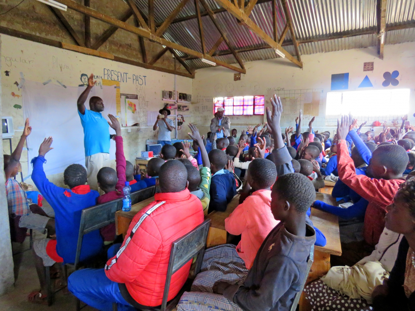 A classroom of students in Laikipia County, Kenya, raises their hands to ask questions