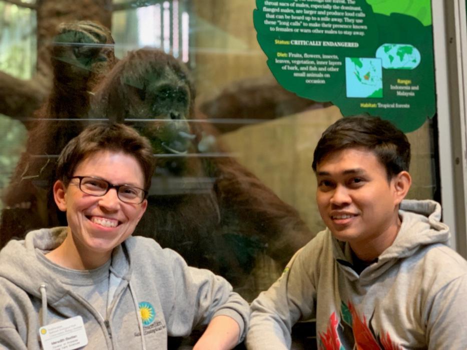 Curator of primates Meredith Bastian and international exchange student Dr. Jati in front of the Smithsonian's National Zoo's orangutan habitat