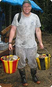 McShea carrying buckets in the field wearing galoshes