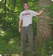 Biologist Chad Stewart stands just outside a fence that keeps deer out of a 10-acre forest study plot at the National Zoo's Conservation and Research Center. A new generation of young trees is thriving inside the fence. (Photo by John Barrat)