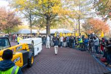 A yellow fork lift carries a crate holding giant panda Bei Bei past a line of videographers and photographers