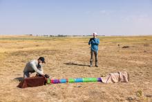 Photo of Smithsonian ecologist Jesse Boulerice (left) releasing a prairie dog to run through a plastic tunnel. Researcher Rory Wilson looks on.