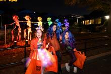 Boo at the Zoo. Three costumed children standing in front of a rainbow skeleton display.