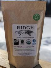 a coffee bag with an image of a bird perched on a pine branch