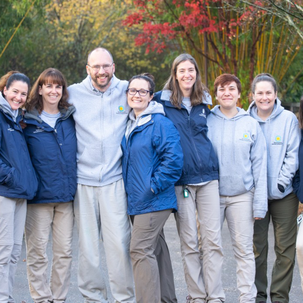 Nine members of the panda keeper team, who are smiling and dressed for cold weather, at the Smithsonian's National Zoo.