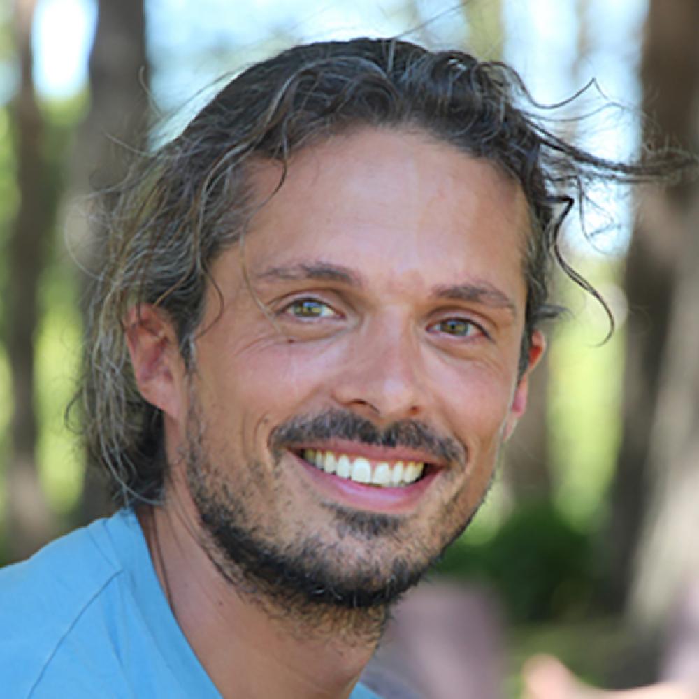 A smiling scientist with a beard and long hair.