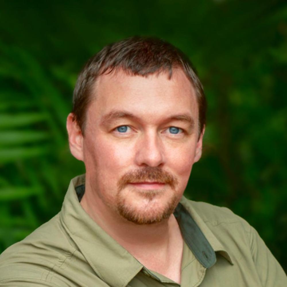 A male scientist with blue eyes and a green shirt