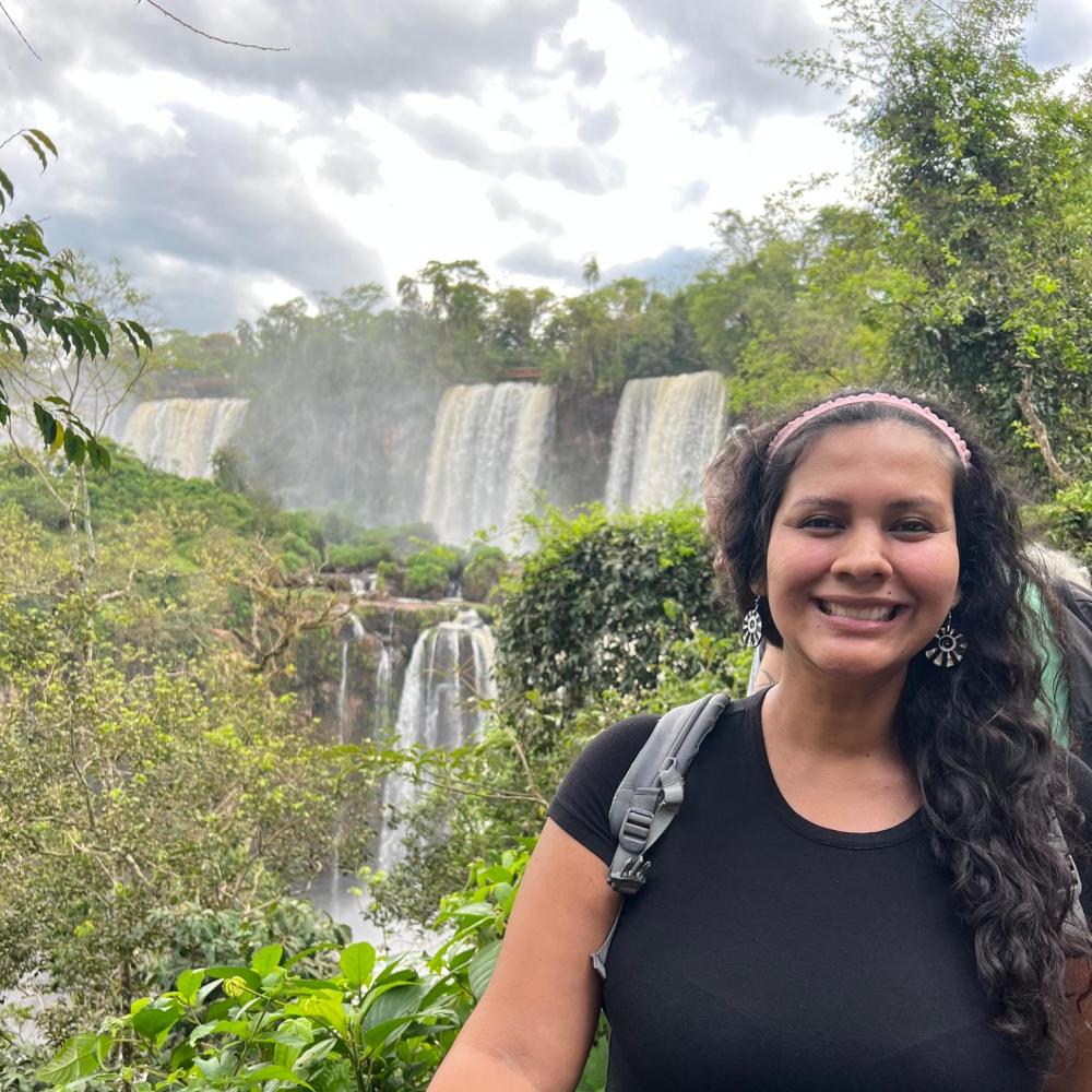 Headshot of a woman in front of a towering waterfall. 