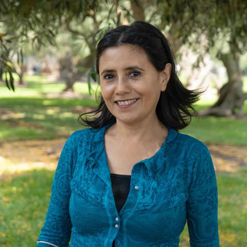 Headshot of a dark-haired woman in a blue sweater. 