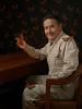 Portrait of man in a tan worksuit smiling at the camera as an orange butterfly perches on his finger.