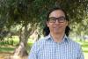 Headshot of a man with glasses in front of a lush tree.