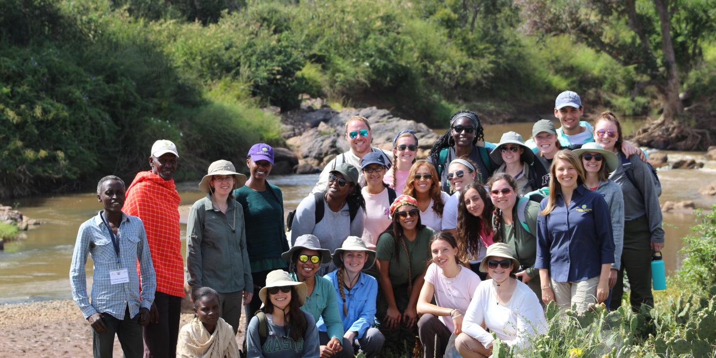 A group of George Mason University undergrad students pose for a photo in the field in Kenya